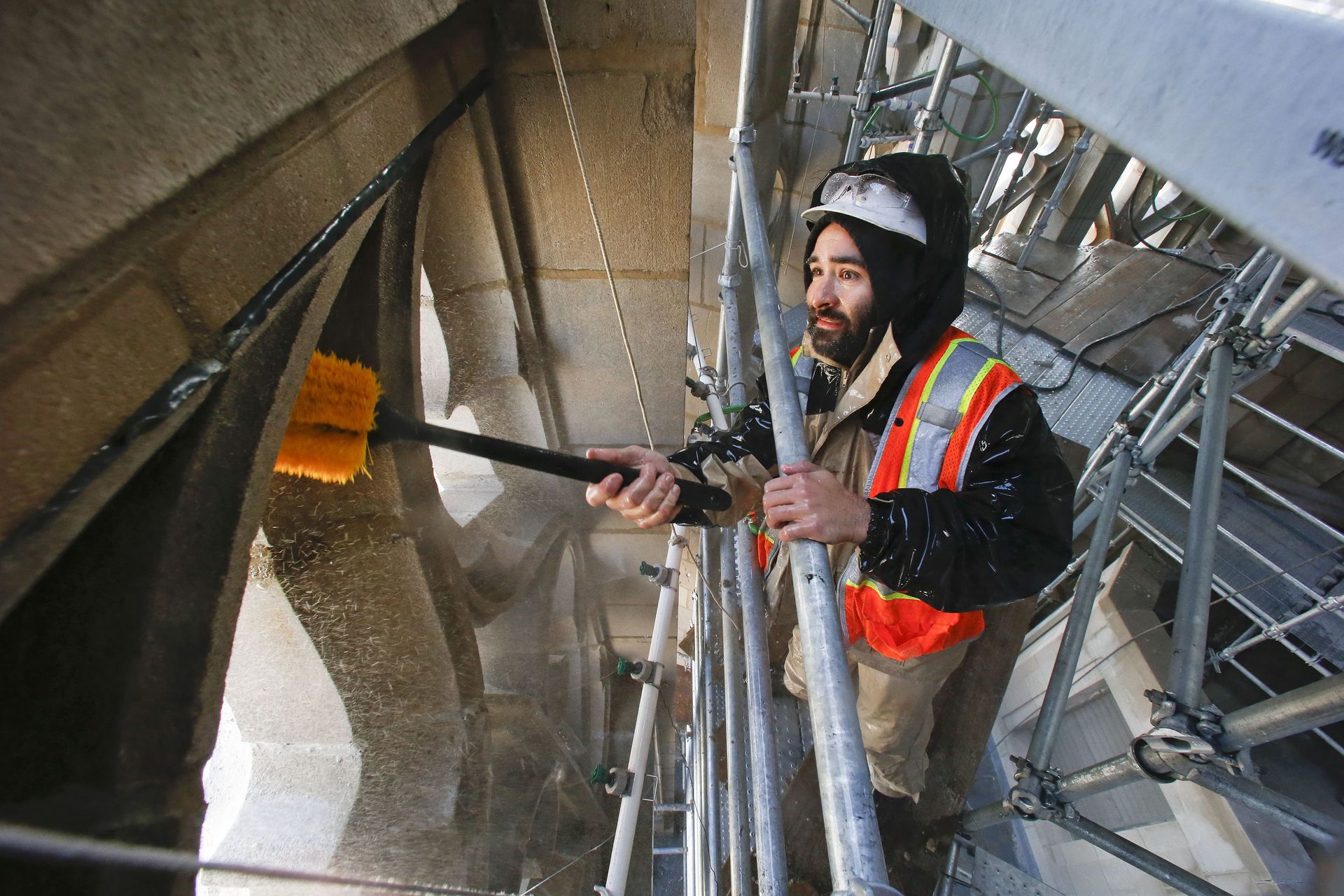 RestoreWorks crew member performing restorative cleaning on historic limestone tracery at Tribune Tower in Chicago using soft bristle brush and scaffold access.