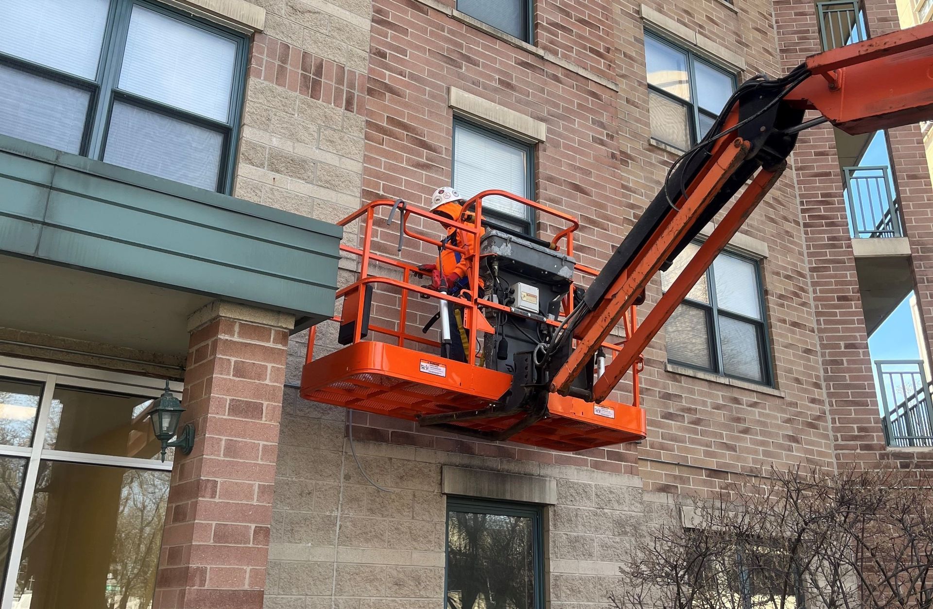 RestoreWorks crew member caulking masonry control joints at South Park Plaza in Chicago using an aerial lift for exterior access.