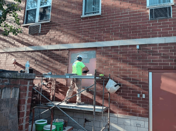 RestoreWorks mason performing exterior brick repairs on an occupied residential building to improve envelope performance while minimizing interior disruption.