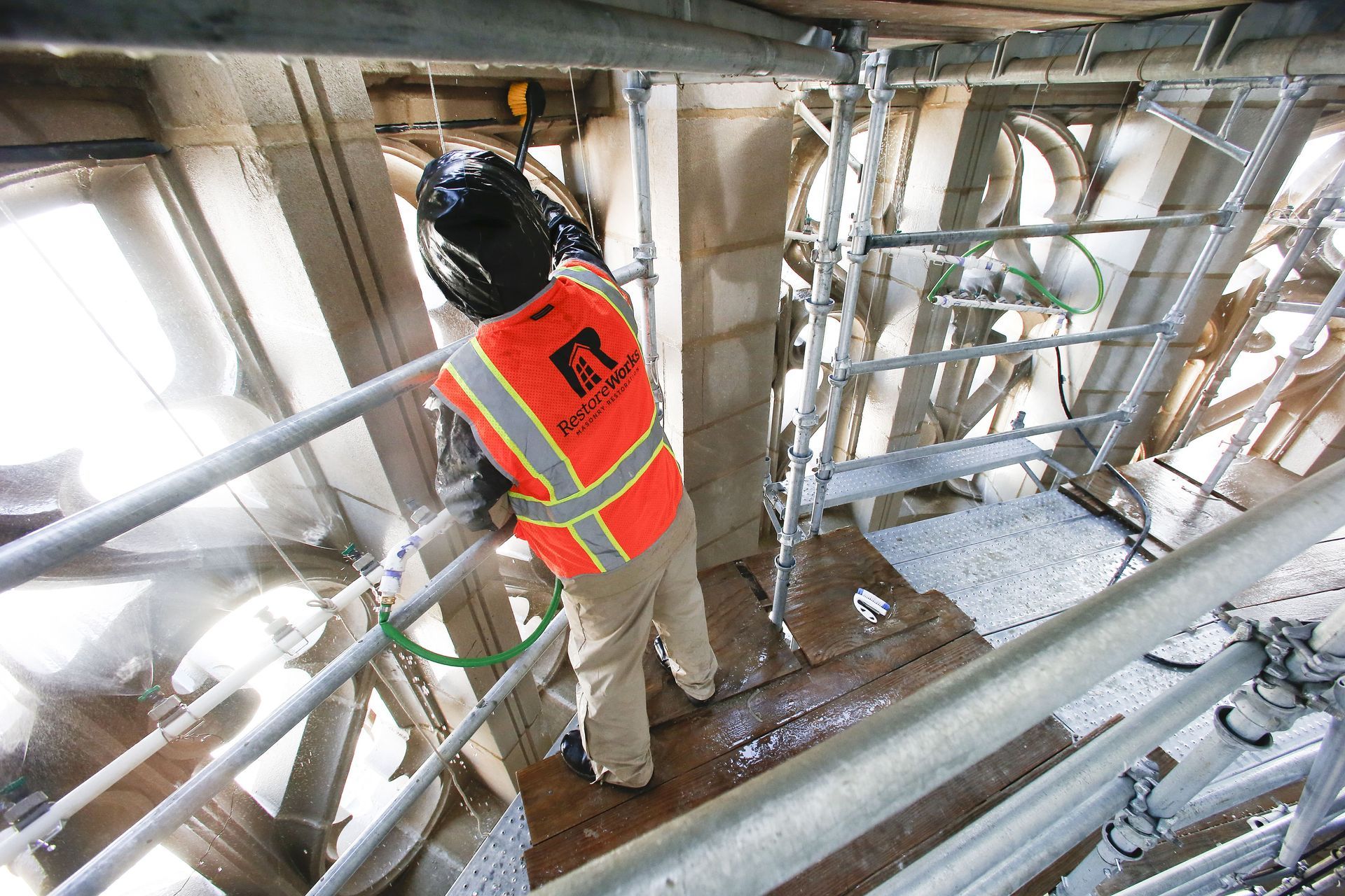 RestoreWorks crew member performing restorative cleaning on ornate limestone tracery at Tribune Tower Residences using multi-level scaffolding and controlled access to reach recessed façade surfaces.