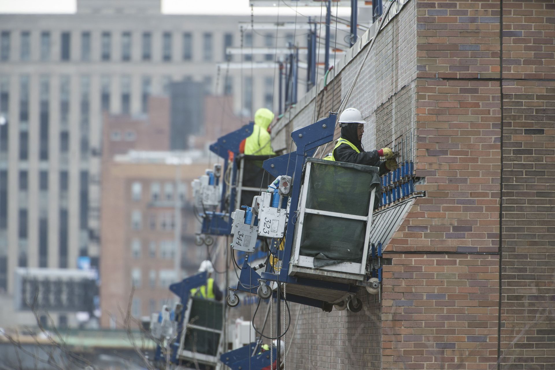 RestoreWorks crews performing facade restoration at the University of Illinois at Chicago’s ETMSW Building using suspended scaffolding to address masonry deterioration, failing lintels, and moisture infiltration on occupied academic facilities.