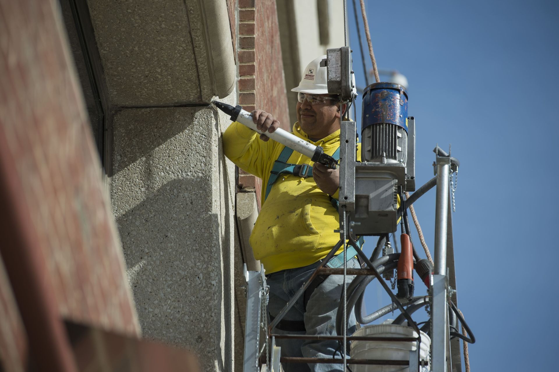 RestoreWorks employee applying sealant during a caulking repair on a Chicagoland hospital facade.