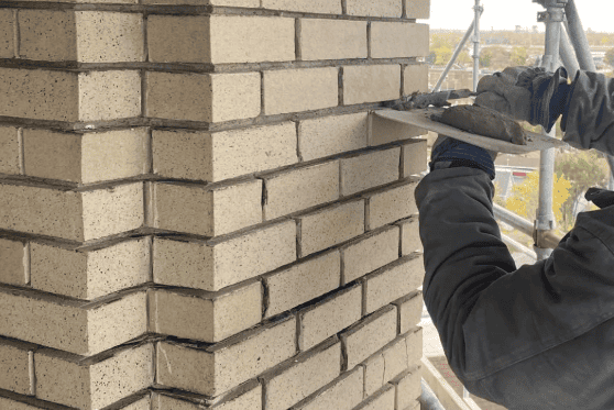 RestoreWorks mason performing tuckpointing on a brick belltower in Northwest Indiana.