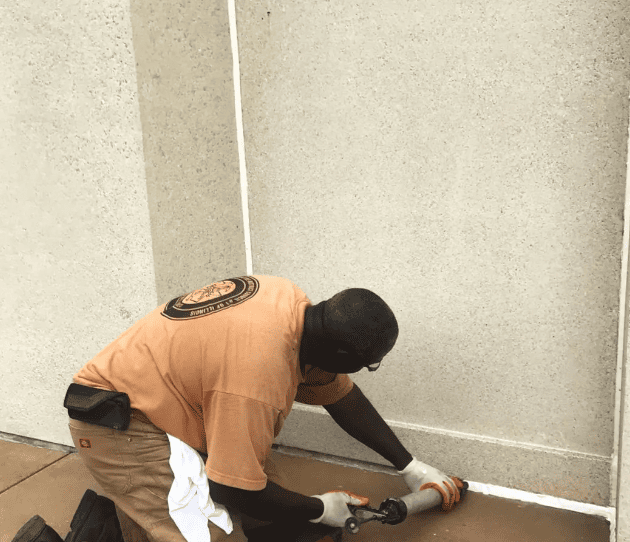 Masonry restoration technician performing exterior sealant maintenance as part of a coordinated building envelope repair strategy.