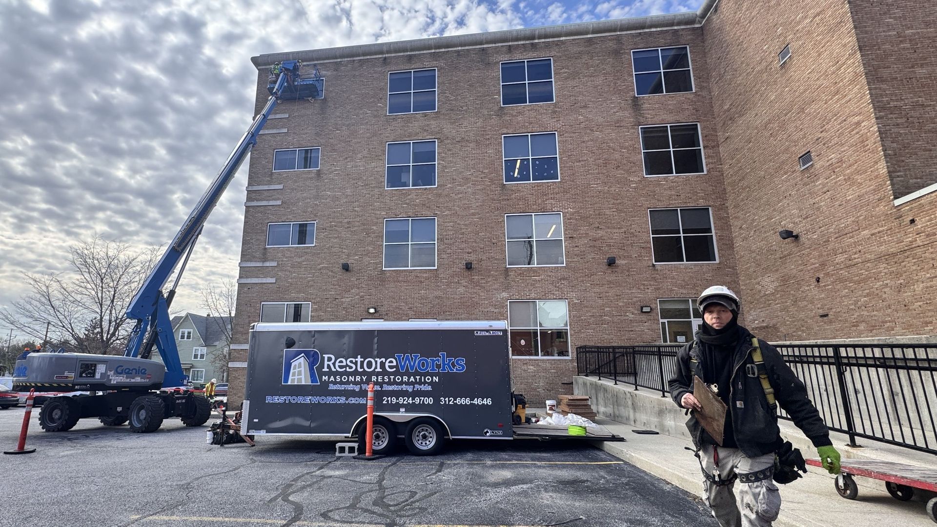 Wide view of east elevation during commercial sealant replacement project. RestoreWorks crew uses boom lift to access window perimeters and apply DOWSIL 795 sealant to over 663 linear feet of masonry-to-window joints on multi-story brick façade.