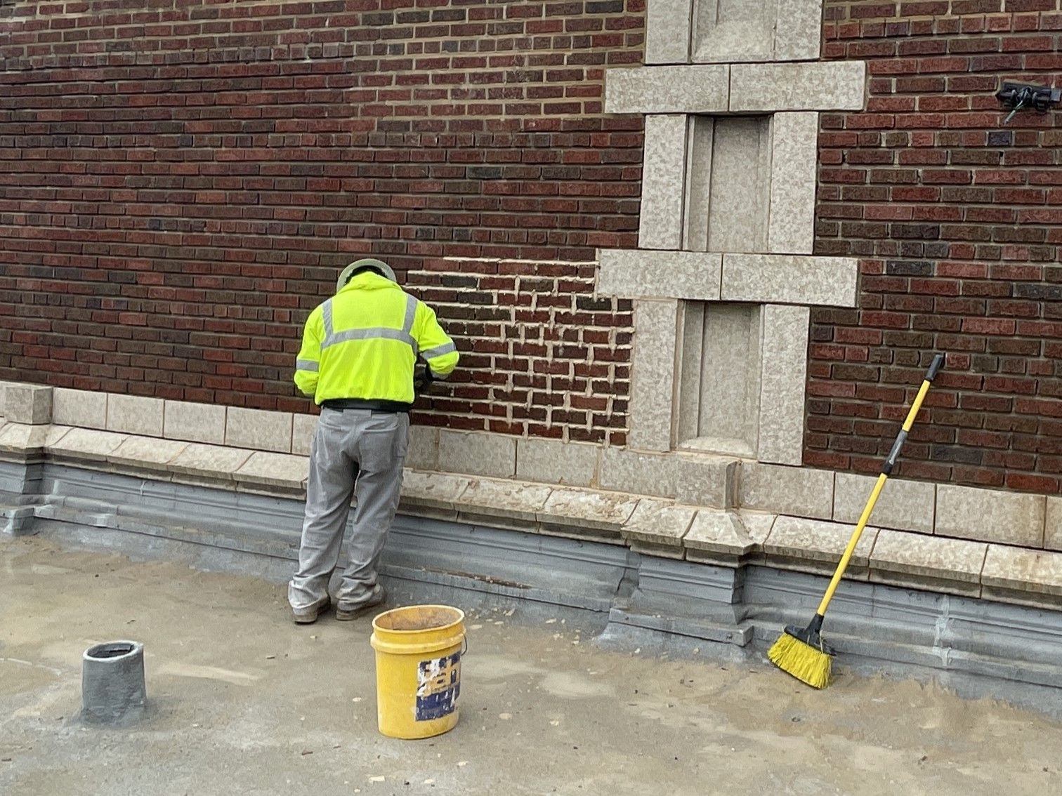 RestoreWorks crew member cleaning brick masonry at Evanston High School, removing surface buildup to restore the facade’s original appearance.