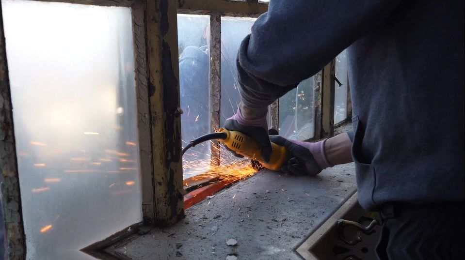 Worker using power tool to restore window frame