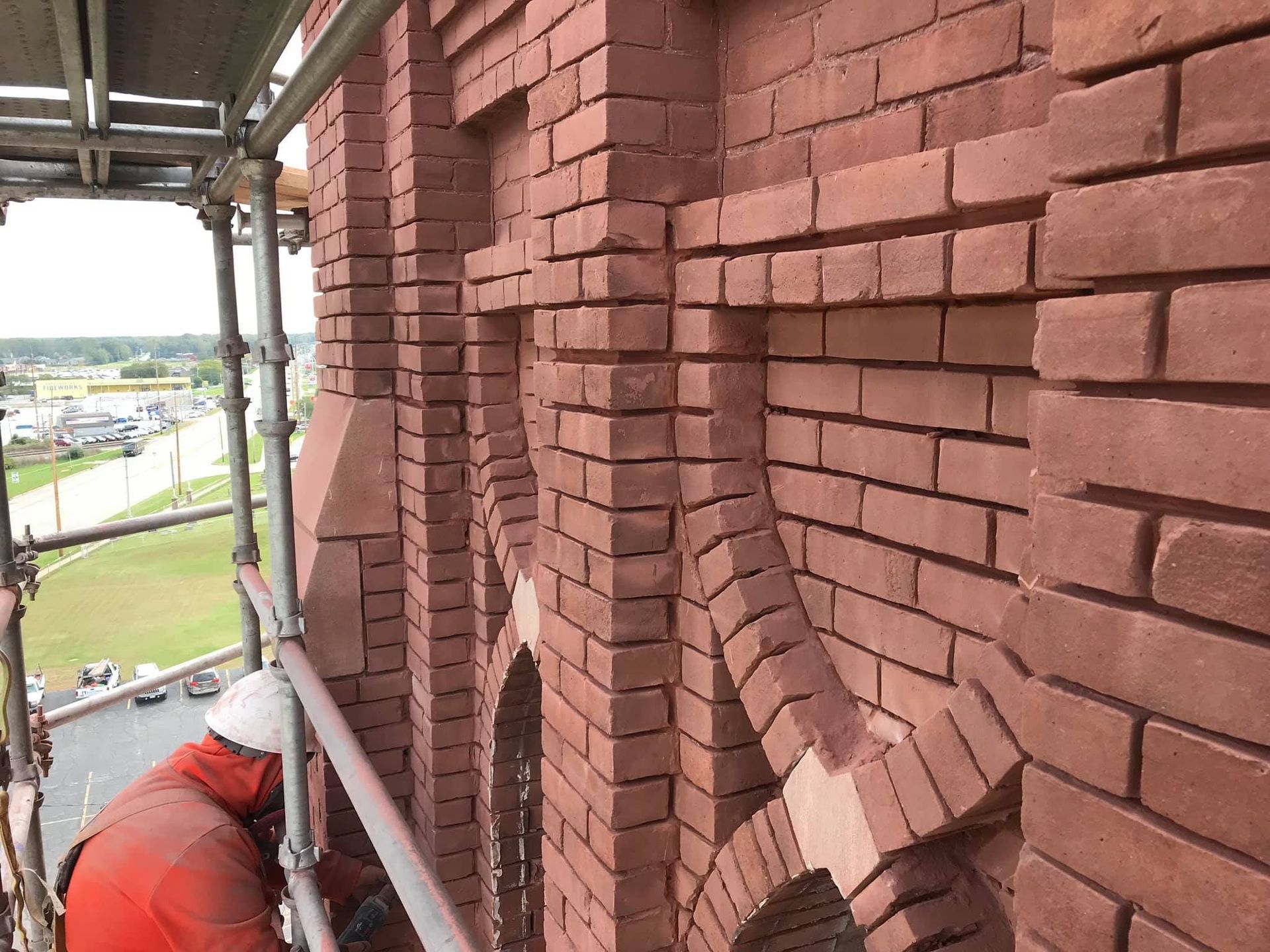 Mason performing tuckpointing on historic brick façade of St. Joseph Catholic Church in Dyer, Indiana using scaffolding.