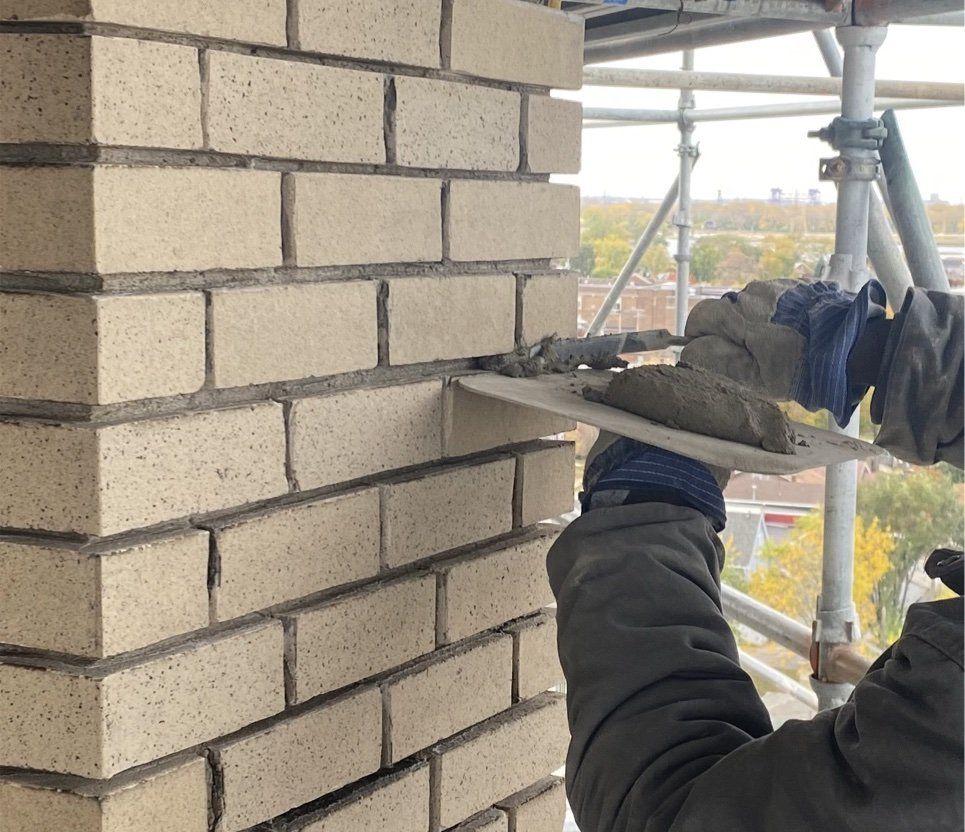 A building undergoing tuckpointing, with a worker repairing mortar joints