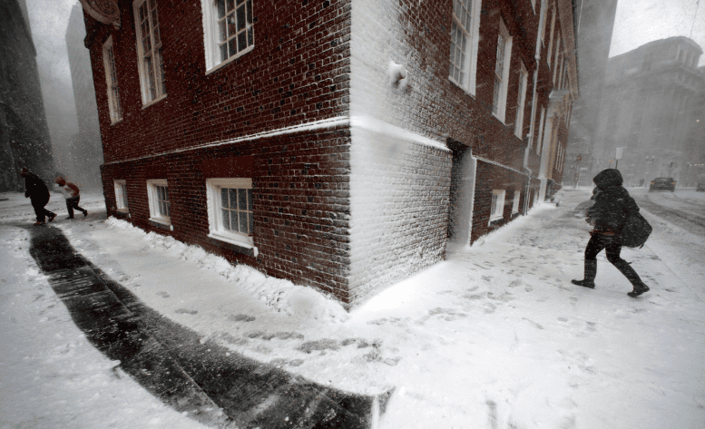 Wind-driven snow hitting a brick building façade during a winter storm, forcing moisture into masonry and increasing freeze–thaw damage risk.