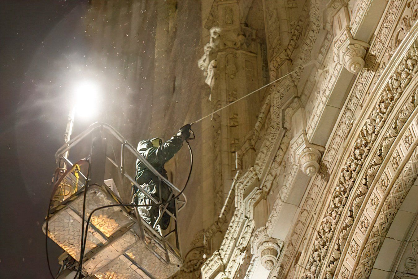 A man is cleaning the Wrigley building with a hose at night.