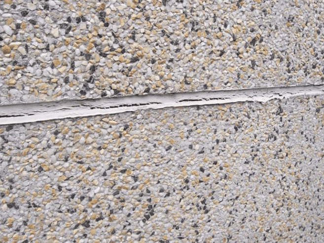 Aging and cracked sealant separating from a precast concrete panel joint, showing early failure that can allow water infiltration and compromise building envelope performance.