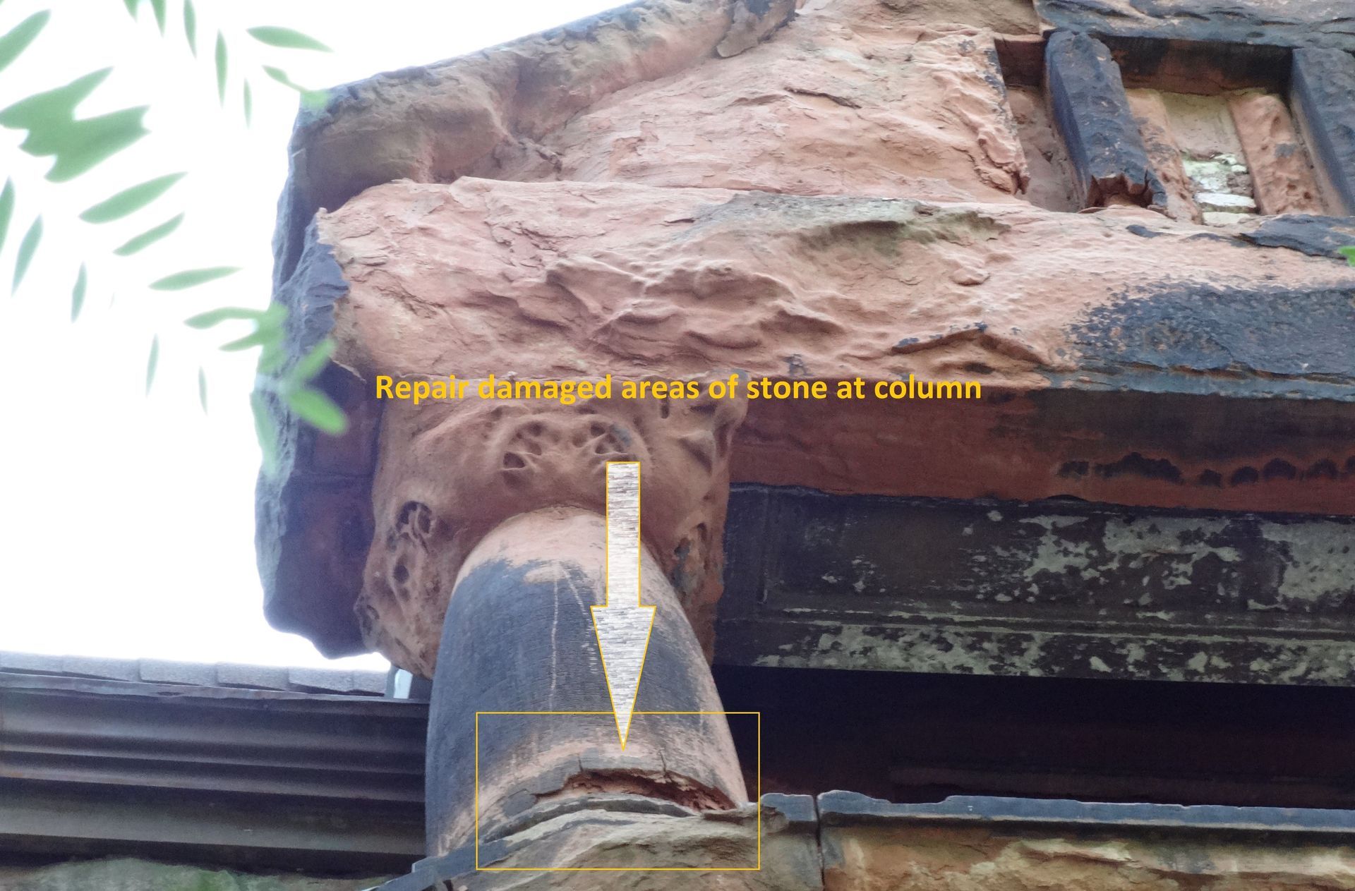 Cracked stone column supporting a balcony, marked for repair during a RestoreWorks masonry inspection of a historic building in need of stone restoration.