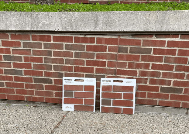 Brick match samples placed against an existing masonry wall to compare color, size, and texture, ensuring material compatibility before restoration work on a commercial building facade.