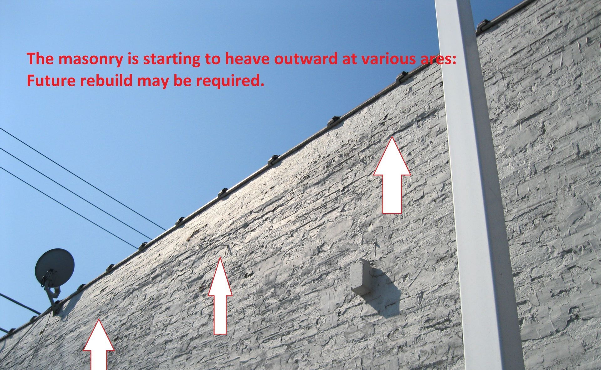 Bulging brick masonry wall showing signs of outward movement, documented during a RestoreWorks inspection with recommendation for potential rebuild.