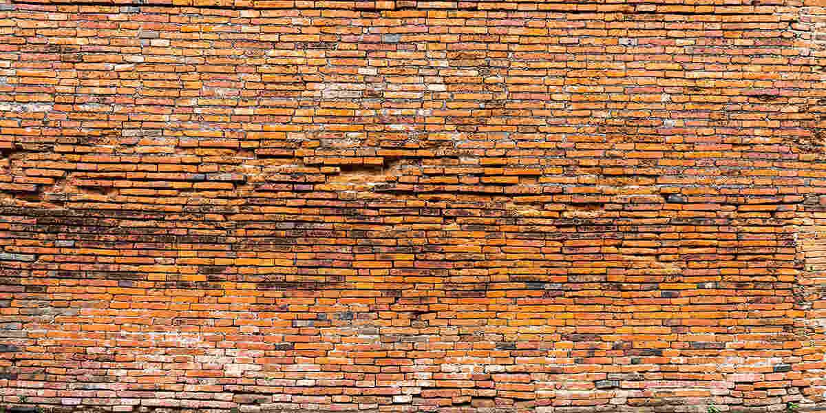 Severely bulging brick wall showing outward displacement from underlying moisture damage or corroded embedded steel, indicating serious structural movement requiring immediate masonry evaluation.