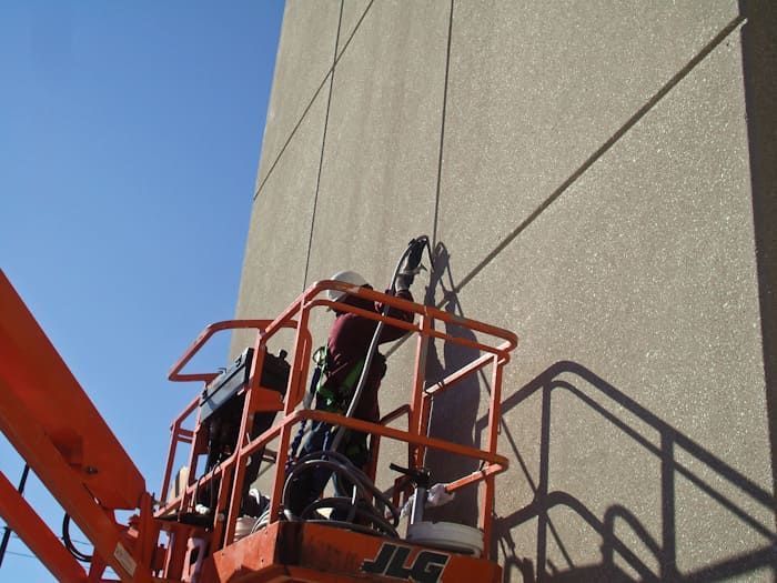 Commercial masonry contractor applying sealant to concrete expansion joints from aerial lift to prevent water infiltration and extend building envelope performance.