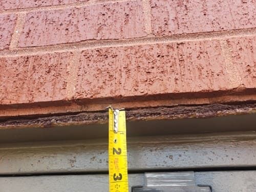 Severely corroded steel lintel beneath a brick facade causing displacement. A clear sign of prolonged moisture exposure and failed or missing flashing in masonry construction.