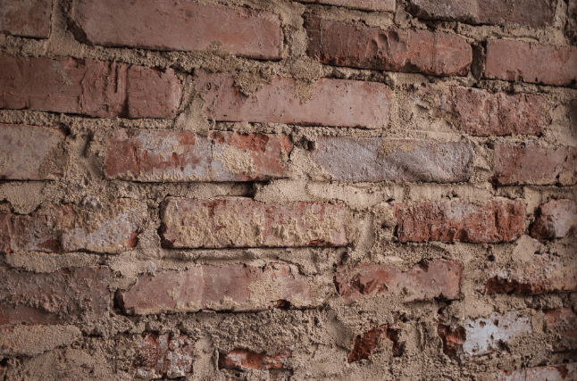 Close-up of a brick wall with crumbling mortar, showing signs of deterioration and the need for masonry repair or repointing.