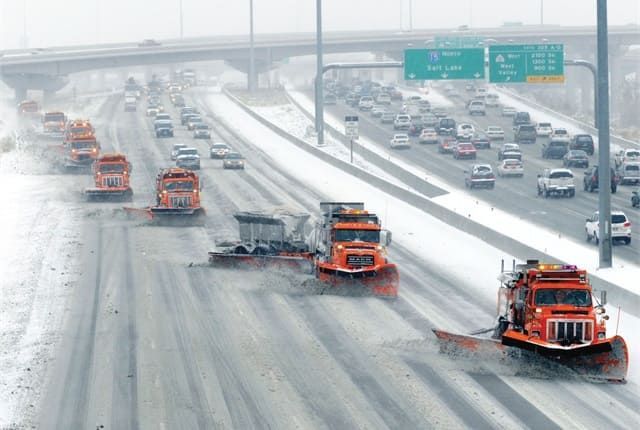 Snowplows spreading de-icing salt on a highway during winter.