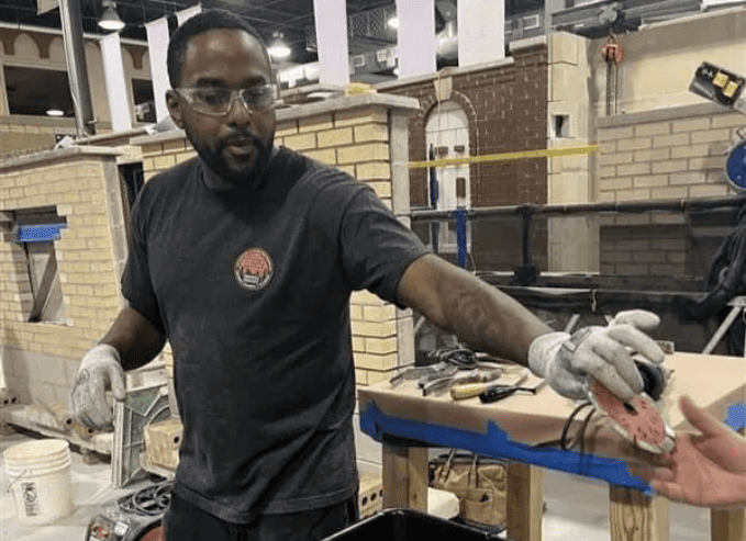 Worker in gloves handling a tool at a workbench in an industrial workshop