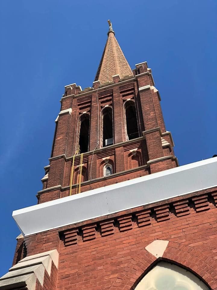 Looking up at a brick church tower with a blue sky in the background