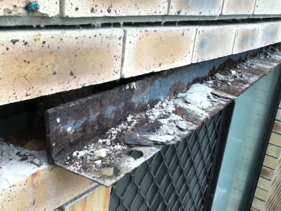 Severely corroded steel lintel causing brick masonry displacement, highlighting urgent need for repair to prevent structural failure.