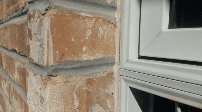 Failed sealant between a brick masonry wall and window frame showing separation that allows water intrusion into the building envelope.