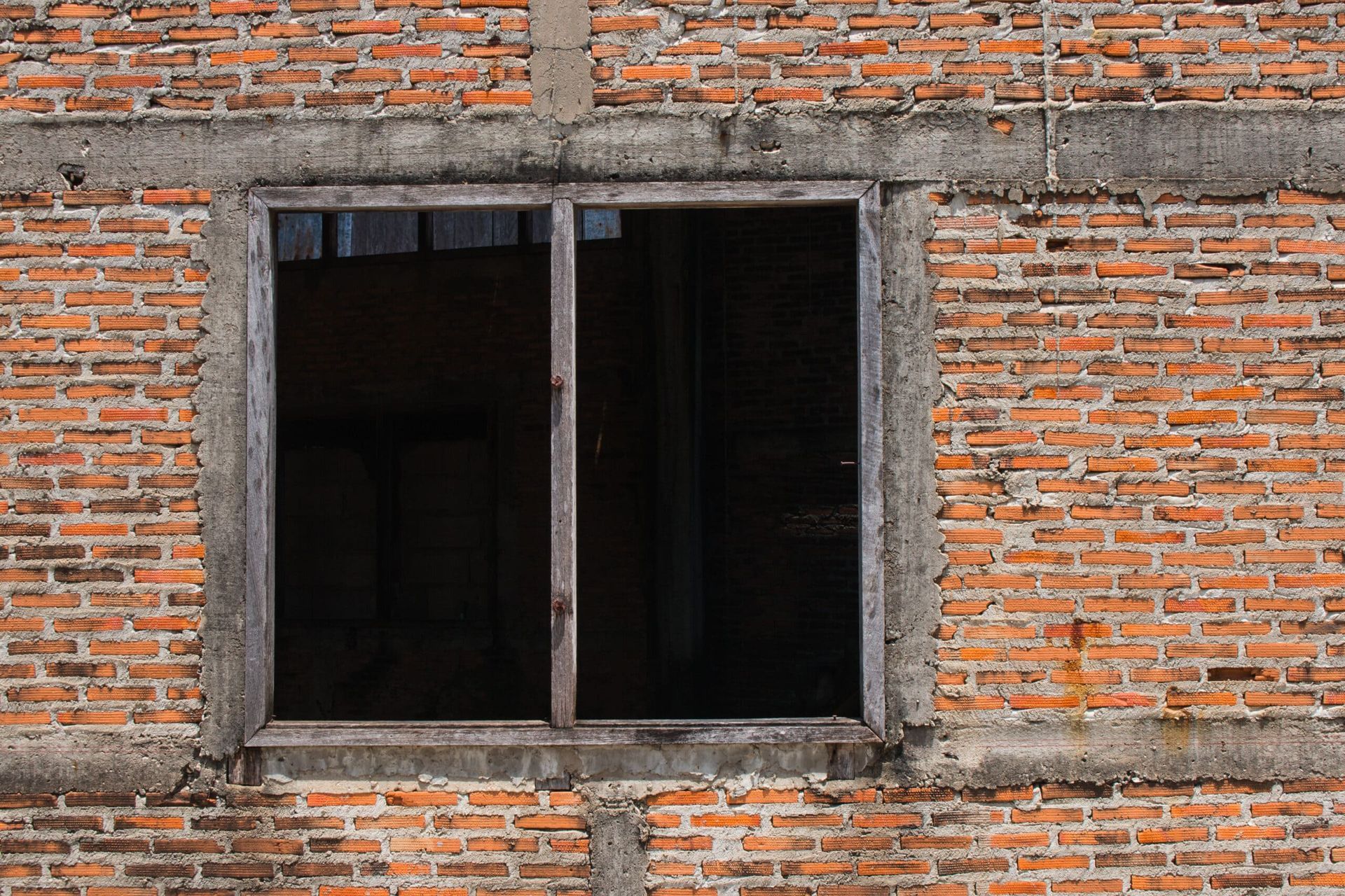 Brick masonry façade with deteriorated mortar joints and cracking around a window opening caused by moisture intrusion and freeze–thaw cycles.