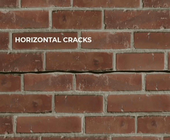 Close-up of a red brick wall with a distinct, straight horizontal crack running through the mortar line.