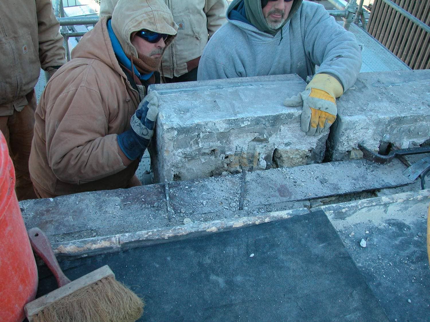 Workers in winter gear handling large ice blocks at an outdoor site