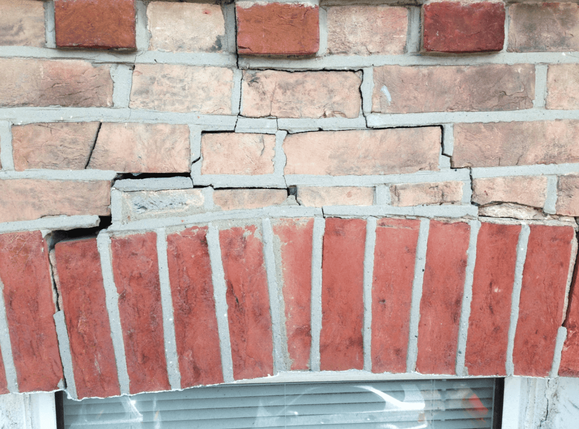 Falling and cracked brick caused by a rusted steel lintel failing above a window—example of emergency masonry repair conditions common in Chicago buildings.
