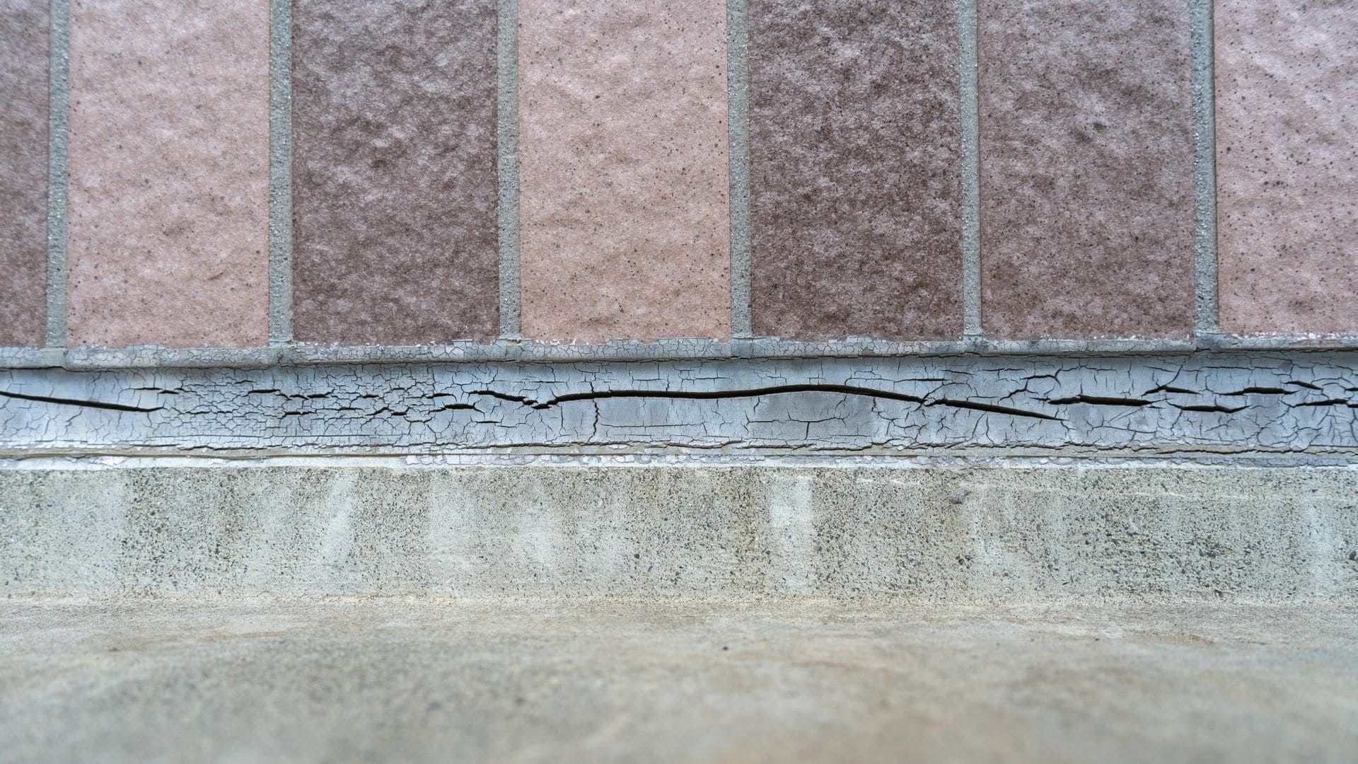 Close-up of cracked and deteriorated mortar joint beneath masonry panels, showing early signs of water infiltration and structural damage documented by RestoreWorks.