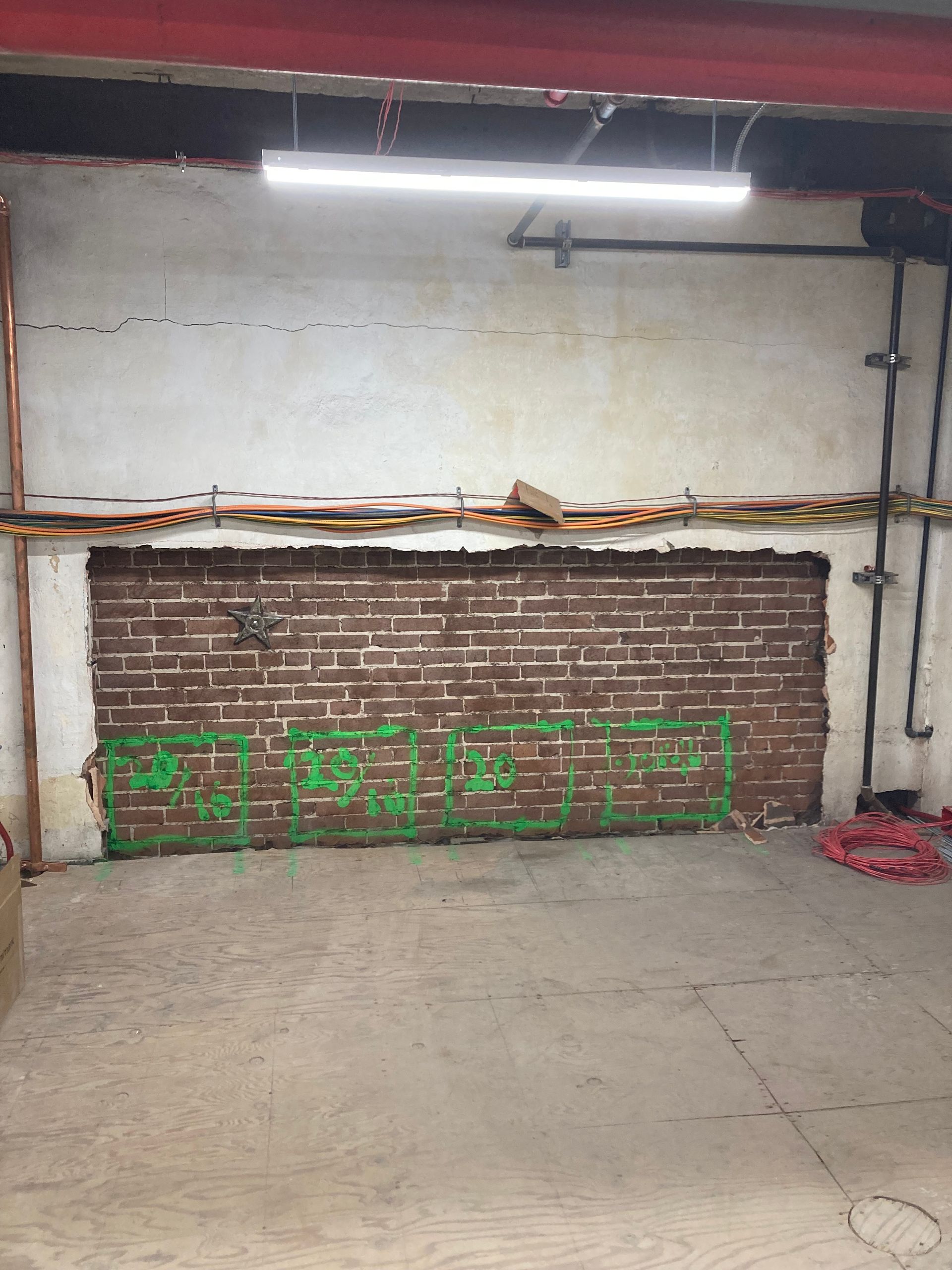 An empty room with a brick wall and green graffiti on it