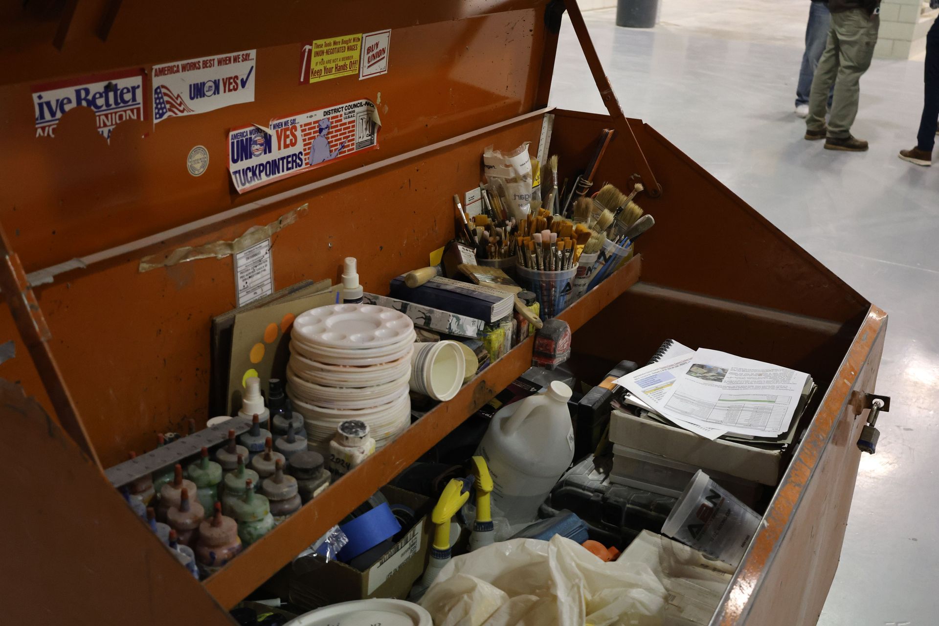 Toolbox filled with brushes, pigments, color palettes, and patching materials used in masonry restoration for color matching and seamless blending of repairs with original stone or brickwork.