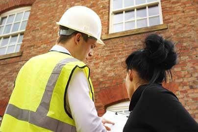 Property manager discussing masonry maintenance plans with a contractor in front of a brick building