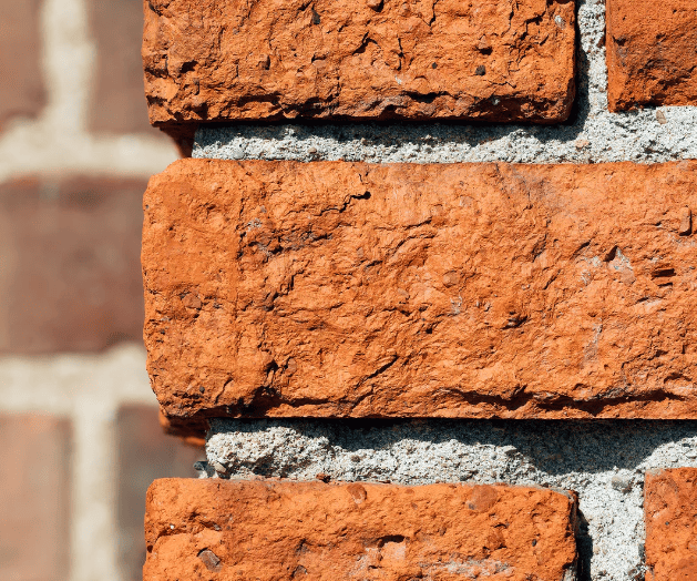 Close-up of recessed and crumbling mortar joints in a brick wall showing early freeze–thaw damage before brick units fail.