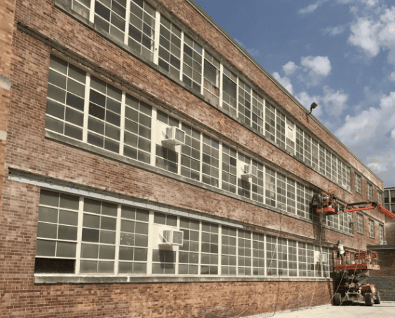 RestoreWorks crews on aerial lifts replacing steel lintels and repairing brick masonry on a large commercial building in Chicago.