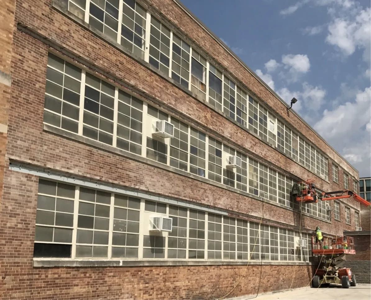 RestoreWorks masonry crews on aerial lifts replacing rusted steel lintels and repairing brickwork on a large commercial building in Chicago.