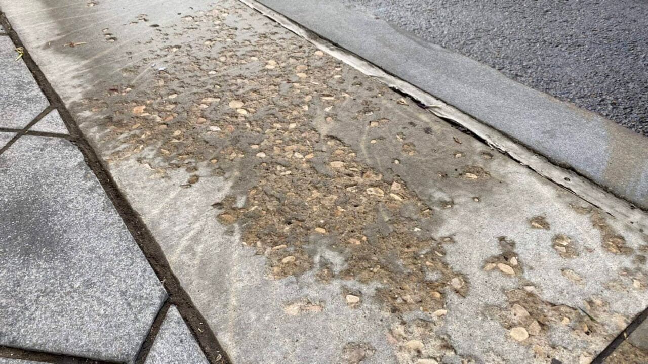 Concrete sidewalk with visible salt scaling and surface erosion caused by repeated exposure to de-icing chemicals and freeze-thaw cycles.