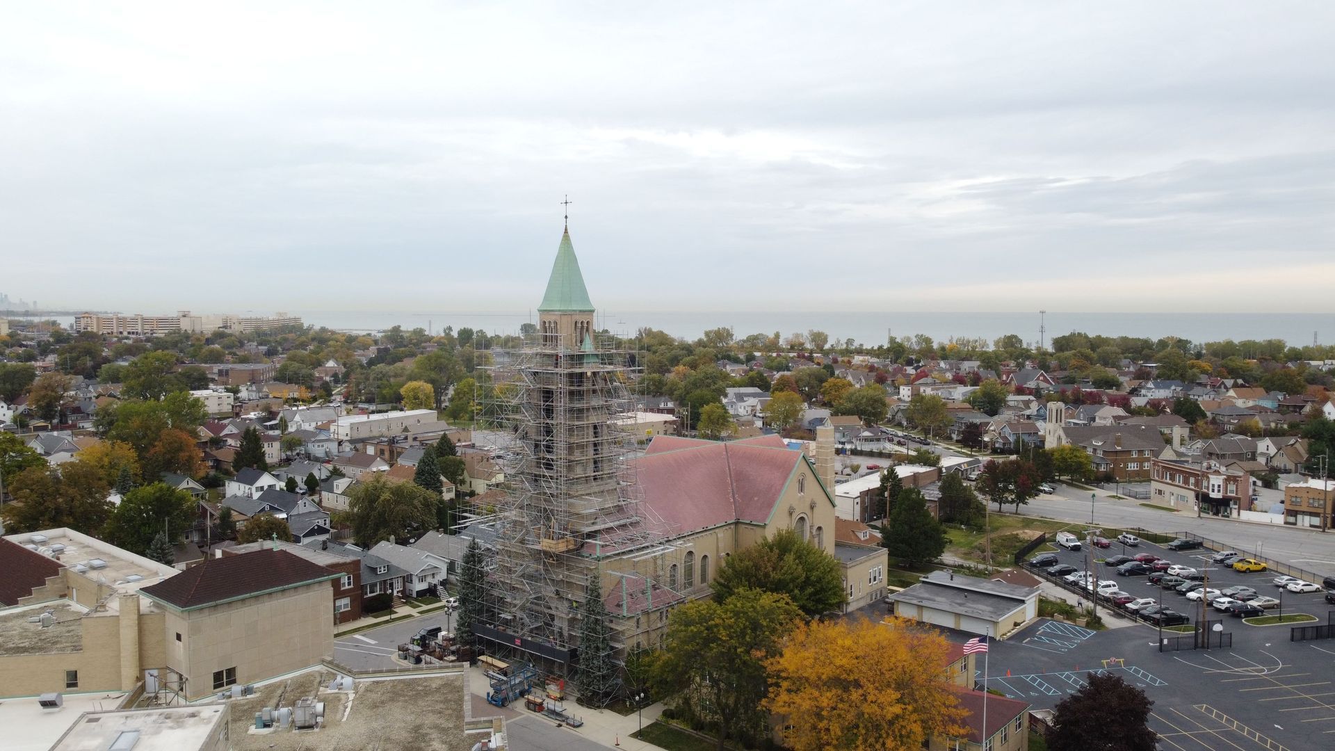 Aerial view of a town center with a tall church steeple, surrounding houses, and autumn trees.