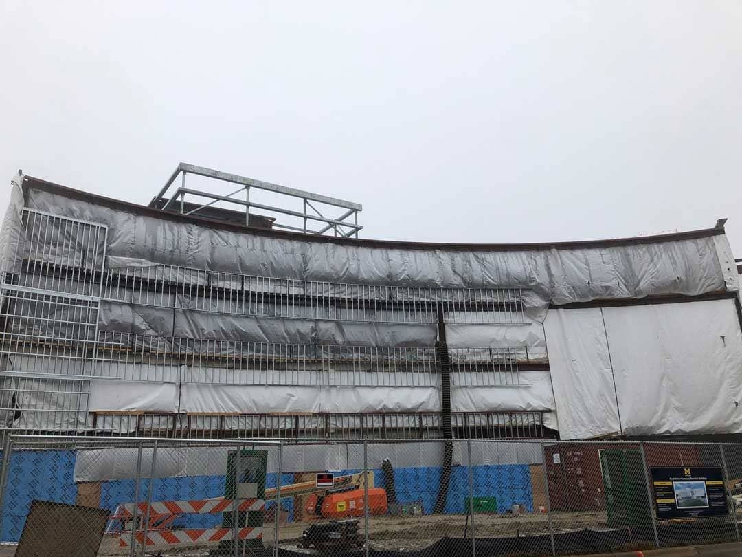 Temporary enclosure surrounding a building to protect ongoing masonry work from weather and maintain proper curing conditions.