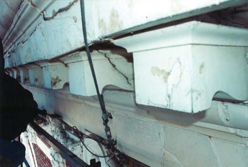 Severe water infiltration causing cracks, efflorescence, and deterioration in historic terra cotta facade, highlighting need for waterproofing and drainage repairs.