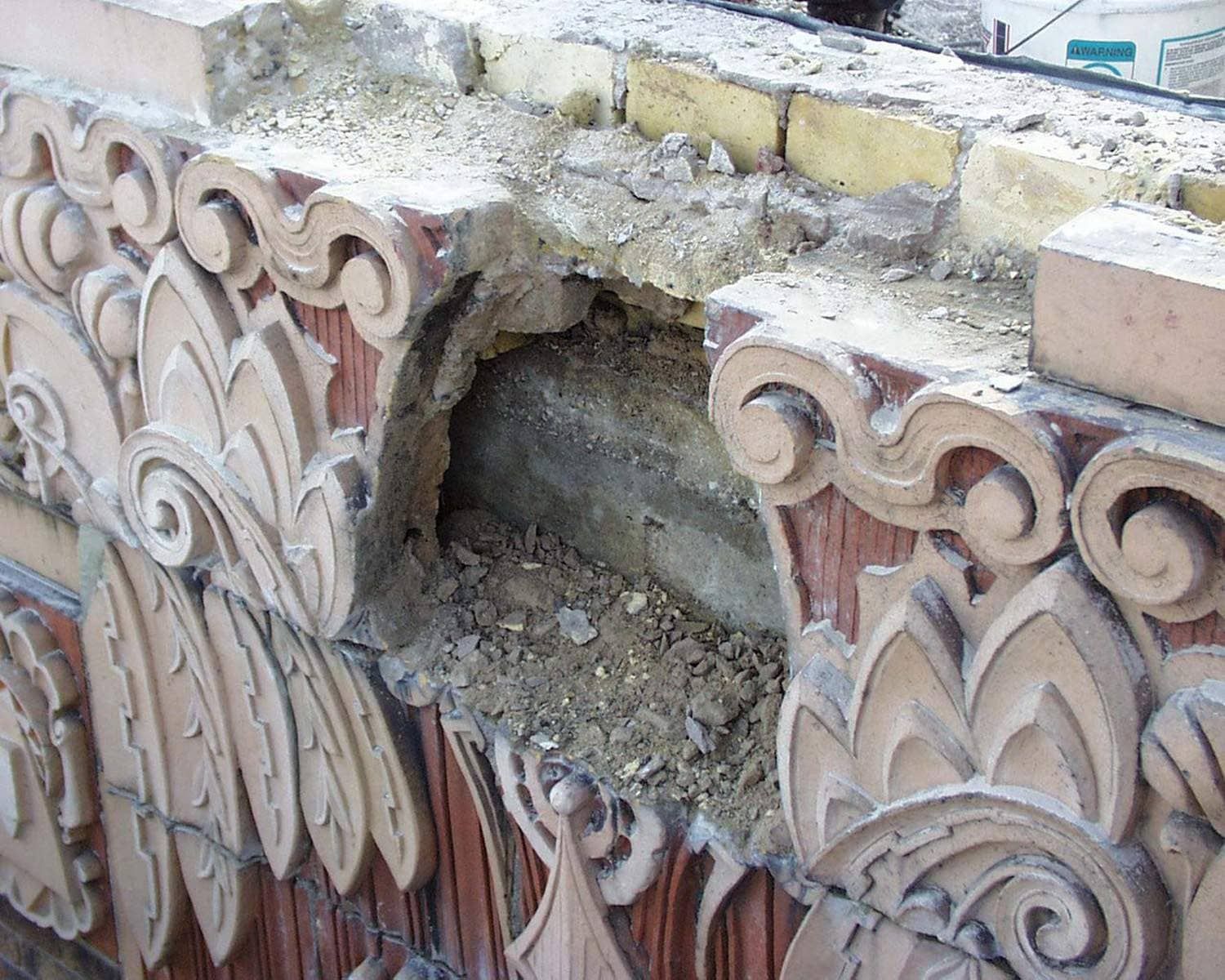 Broken ornate stone trim with a missing section exposing rubble and masonry underneath