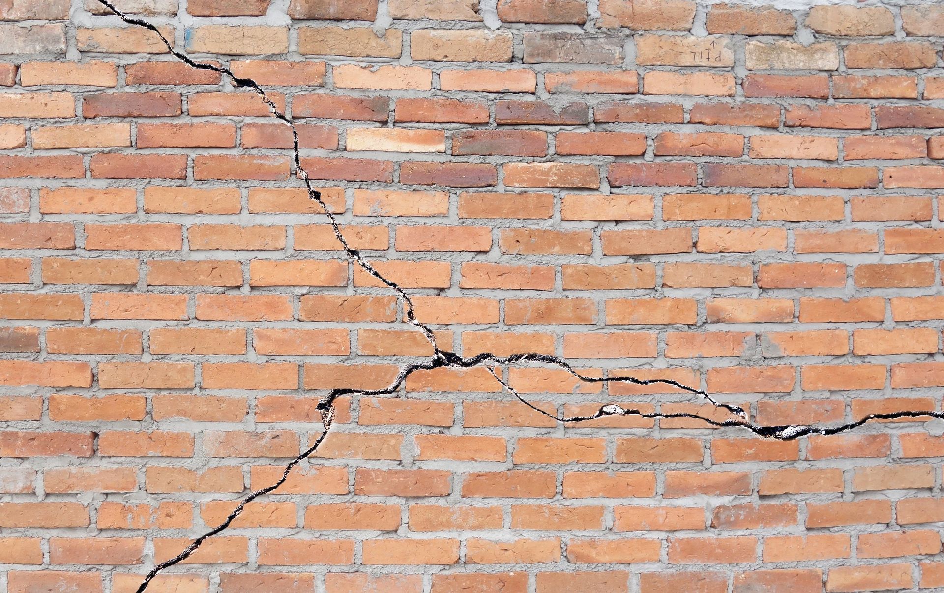Brick wall with large cracks from thermal expansion and structural stress.