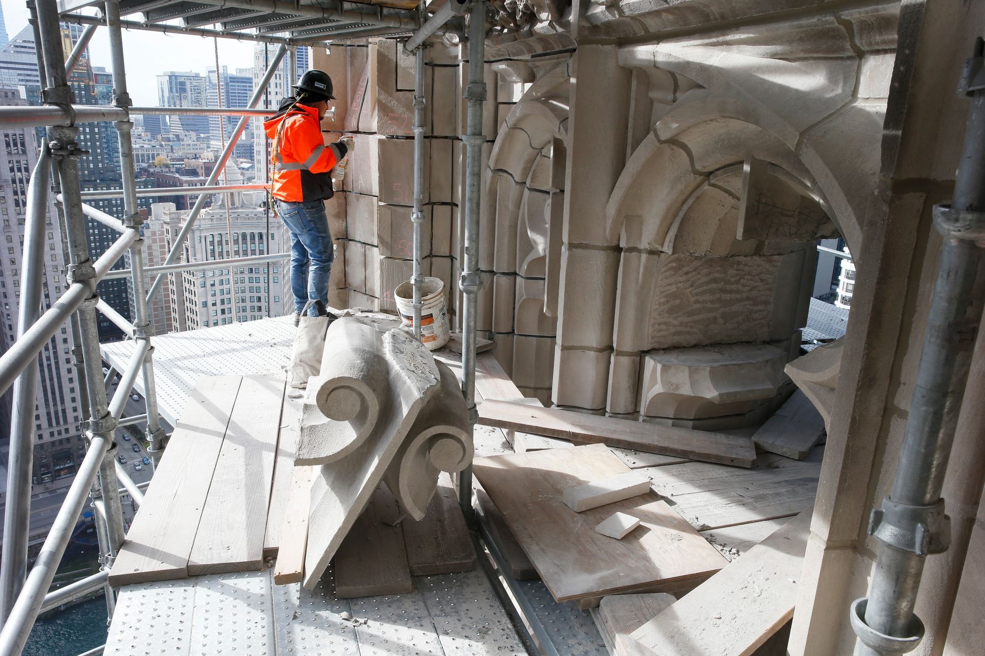 A man is standing on a scaffolding on top of Tribune Tower