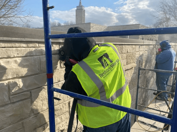 RestoreWorks mason grinding out deteriorated mortar joints on a limestone wall to prepare for tuckpointing and masonry restoration.
