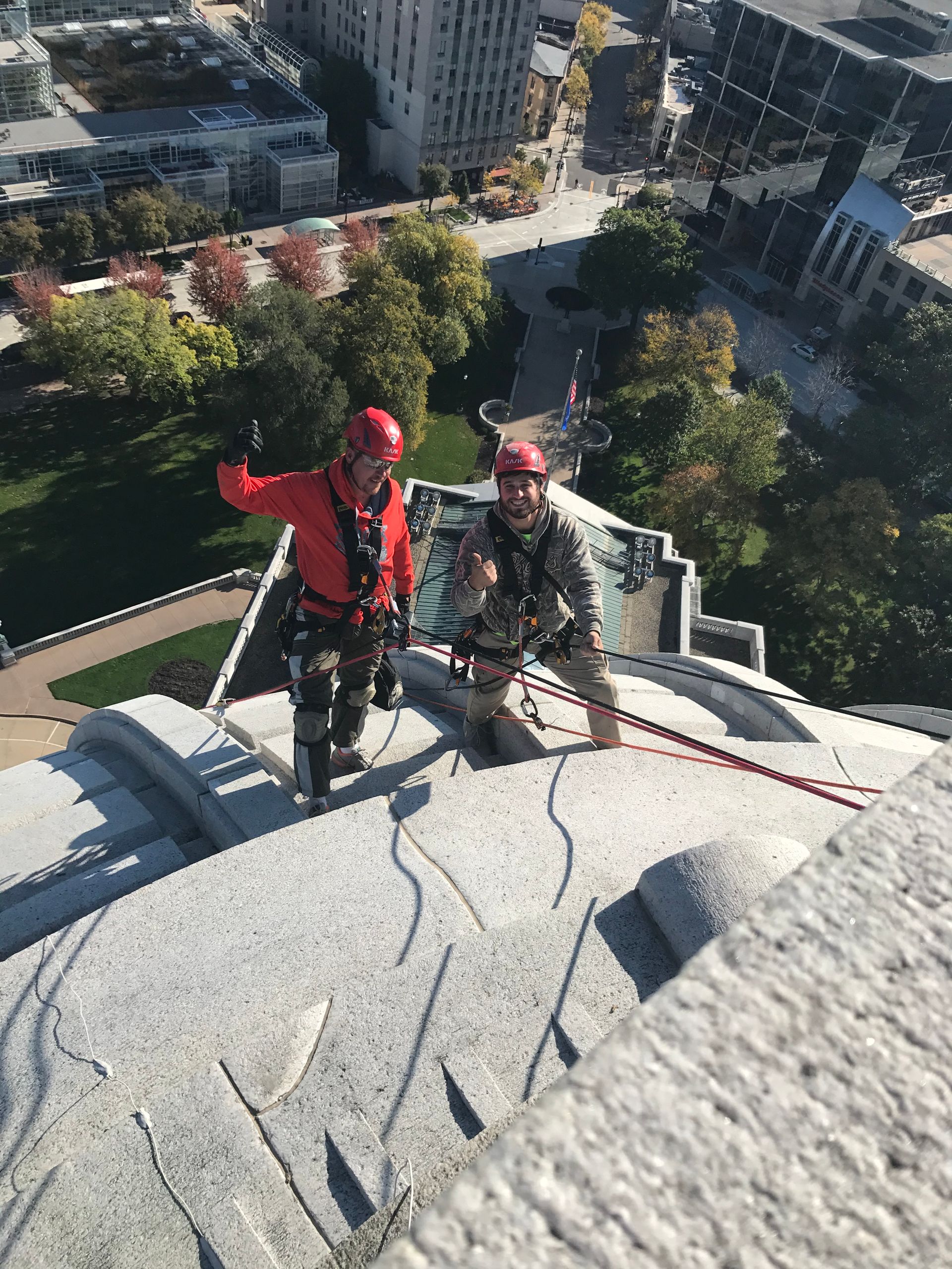 Two men are climbing up the side of the Wisconsin State Capitol