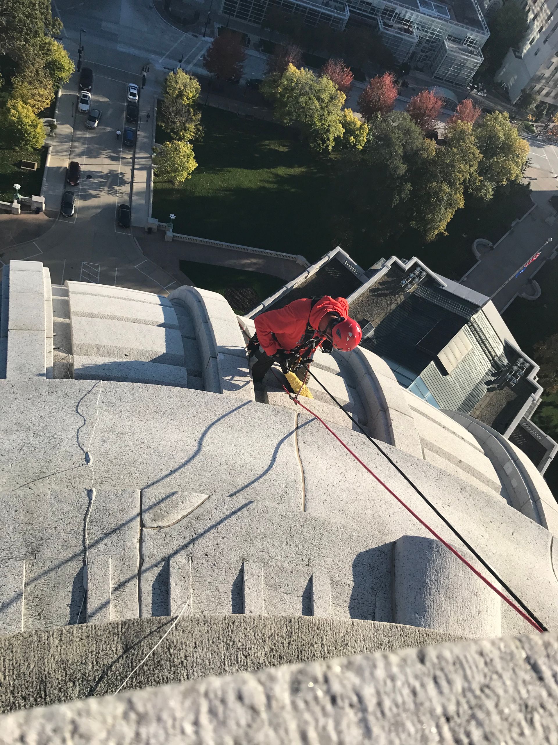 A man in a red jacket is doing restoration on the Wisconsin State Capitol
