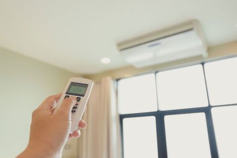One man's hand is pressing the air conditioner remote in his hand to rest
